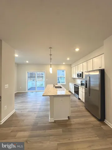 a large kitchen with stainless steel appliances kitchen island a large counter top and a wooden floors