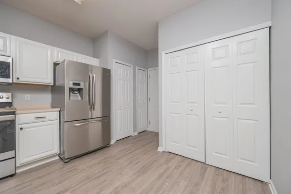 a kitchen with stainless steel appliances a refrigerator cabinets and wooden floor