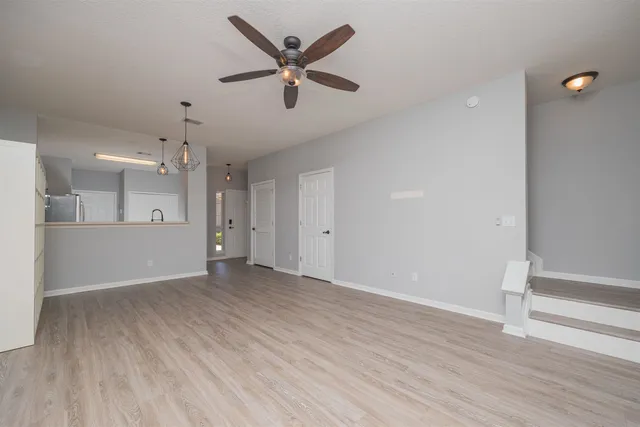 an empty room with wooden floor and a ceiling fan