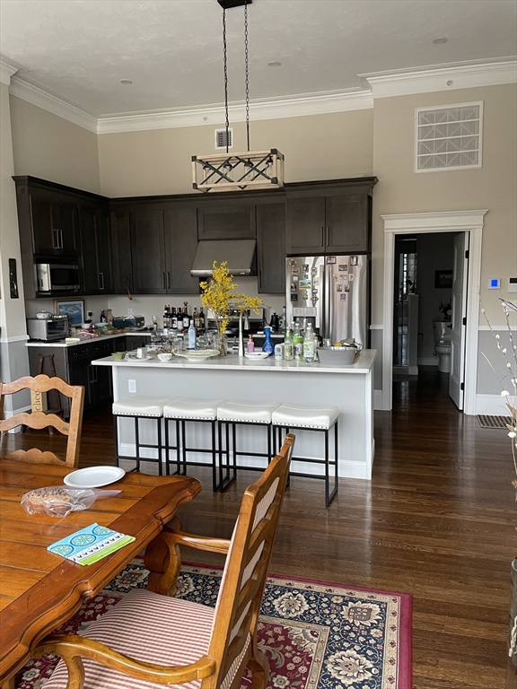a kitchen with stainless steel appliances kitchen island granite countertop a stove top oven a sink a dining table and chairs with wooden floor