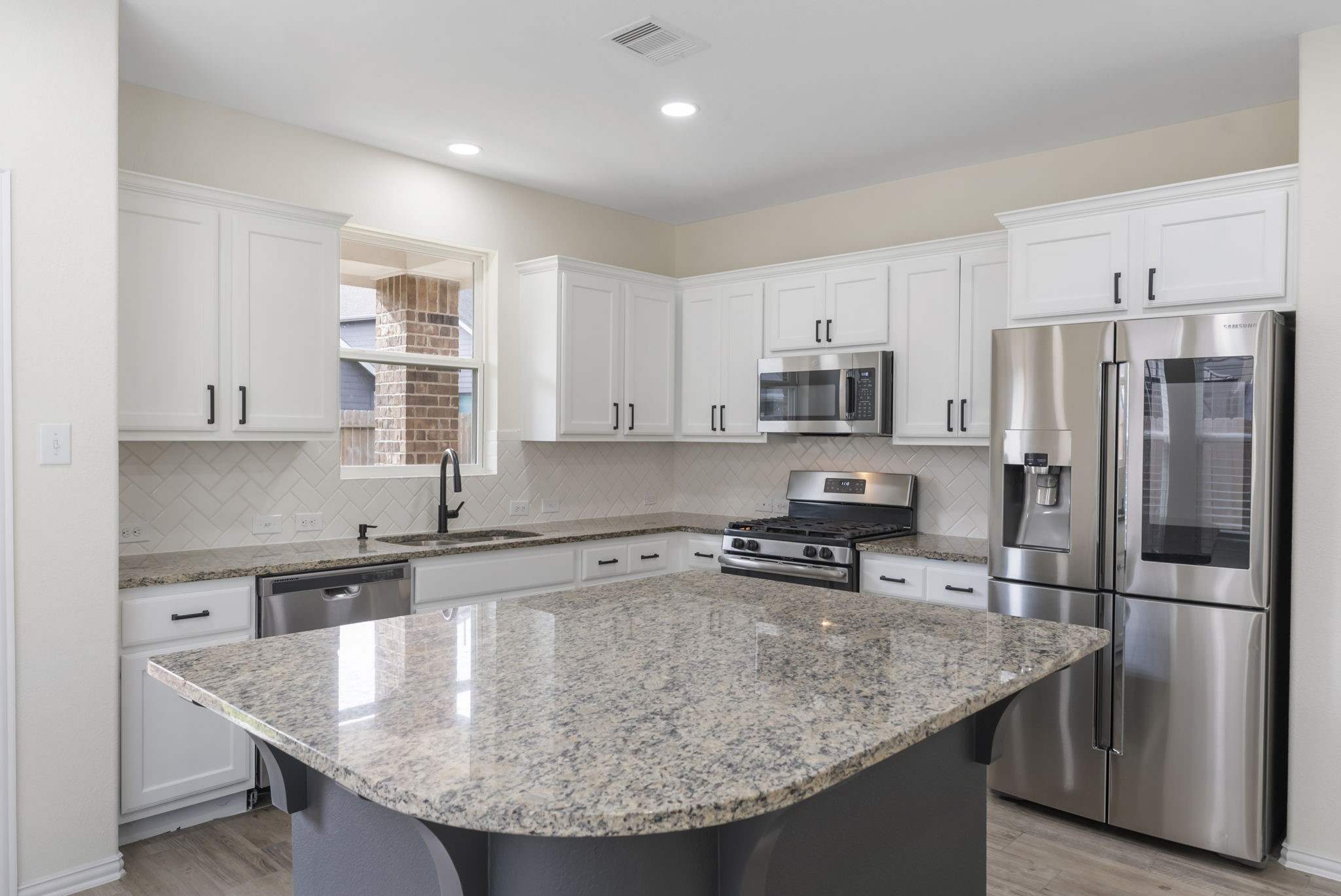 a kitchen with stainless steel appliances granite countertop a sink a stove and refrigerator