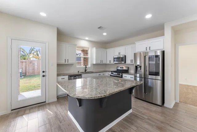 a kitchen with kitchen island a sink stove and refrigerator