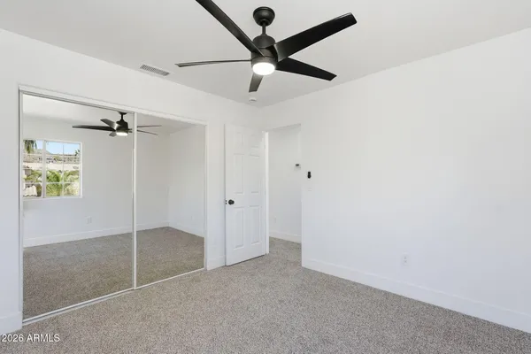 an empty room with windows and fan