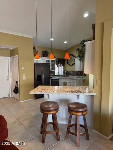 a kitchen with stainless steel appliances kitchen island granite countertop a table chairs and a refrigerator