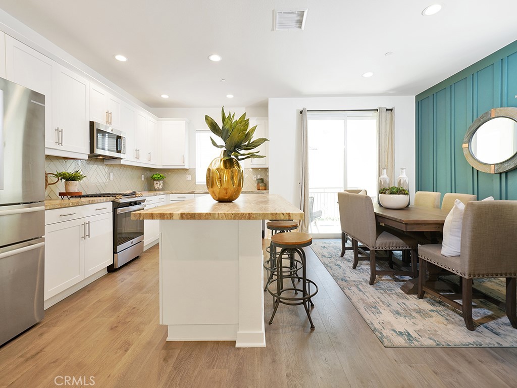 603 Shadowbrook Lake Forest, CA 92610 - Photo 5 of 23 a kitchen with a table chairs a sink dishwasher and cabinets with wooden floor