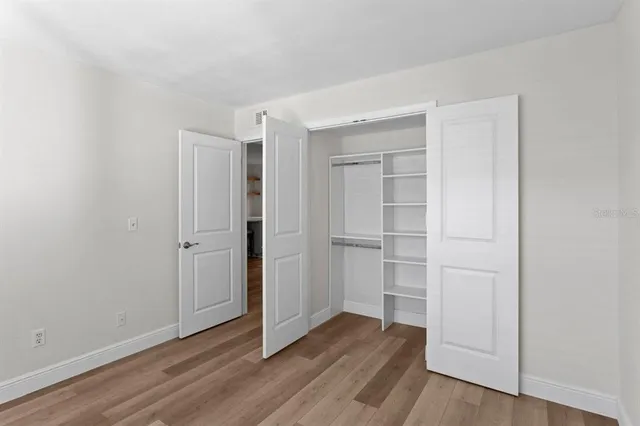a view of an empty room with closet and wooden floor