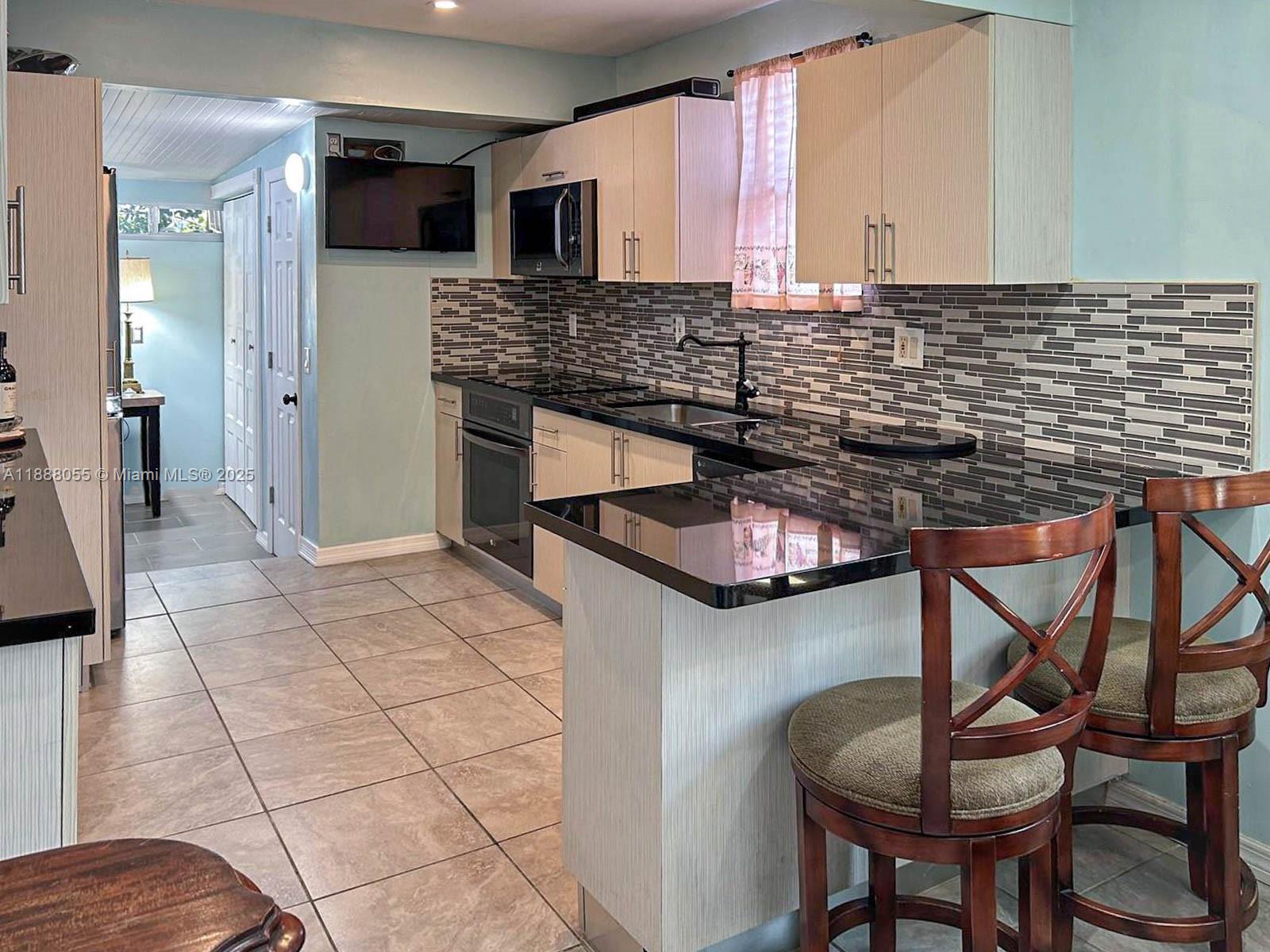 3410 Southwest 24th Street Miami, FL 33145 - Photo 5 of 8 a kitchen with stainless steel appliances kitchen island granite countertop a stove a sink and a microwave