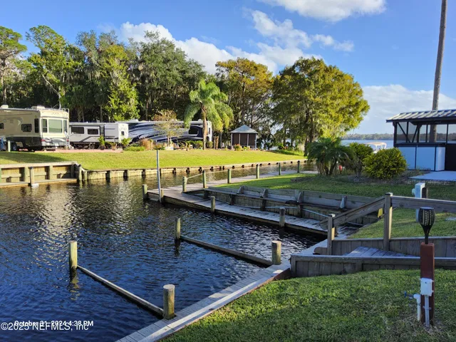 a dining room with furniture a rug a potted plant and a wooden floor
