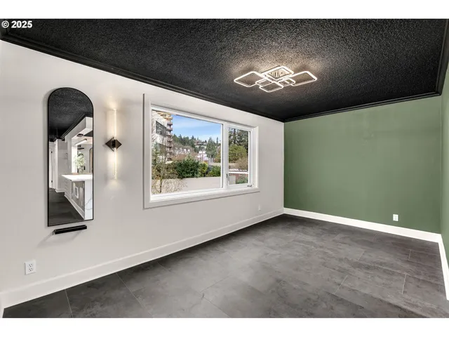 a view of an empty room with chandelier fan and wooden floor