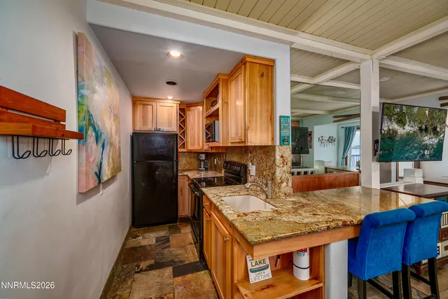 a kitchen with granite countertop kitchen island stainless steel appliances a stove refrigerator sink and cabinets