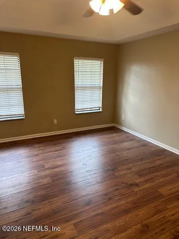an empty room with wooden floor and windows