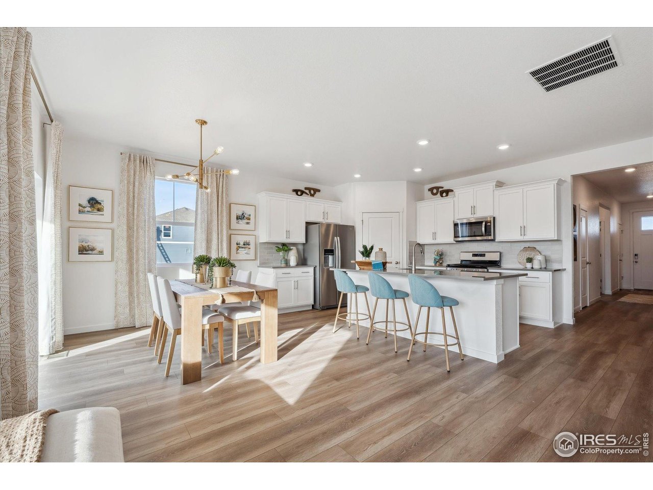 2303 Base Street Fort Lupton, CO 80621 - Photo 8 of 26 a kitchen with a dining table chairs wooden floor cabinets and stainless steel appliances