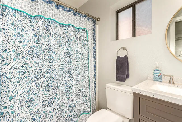 a bathroom with a granite countertop toilet and a sink