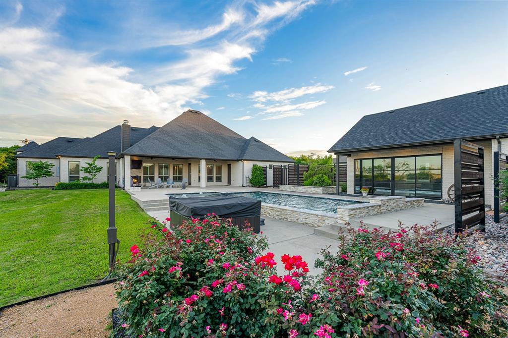 1070 Cornelius Road Rockwall, TX 75087 - Photo 26 of 33 Expansive outdoor living area featuring a rectangular pool, stone-surrounded spa, and a covered patio with an outdoor fireplace
