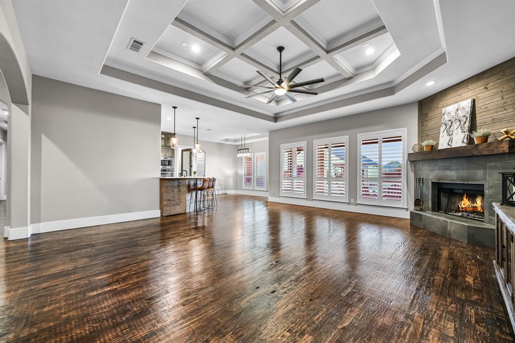 1070 Cornelius Road Rockwall, TX 75087 - Photo 7 of 33 Open-concept living area featuring a coffered ceiling with recessed lighting and ceiling fan, and a fireplace with a stone surround and wood mantel