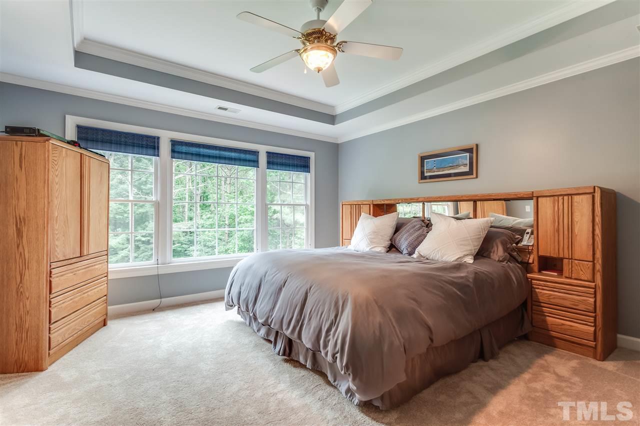 9428 Macon Road Raleigh, NC 27613 - Photo 19 of 25 a spacious bedroom with a bed and a chandelier
