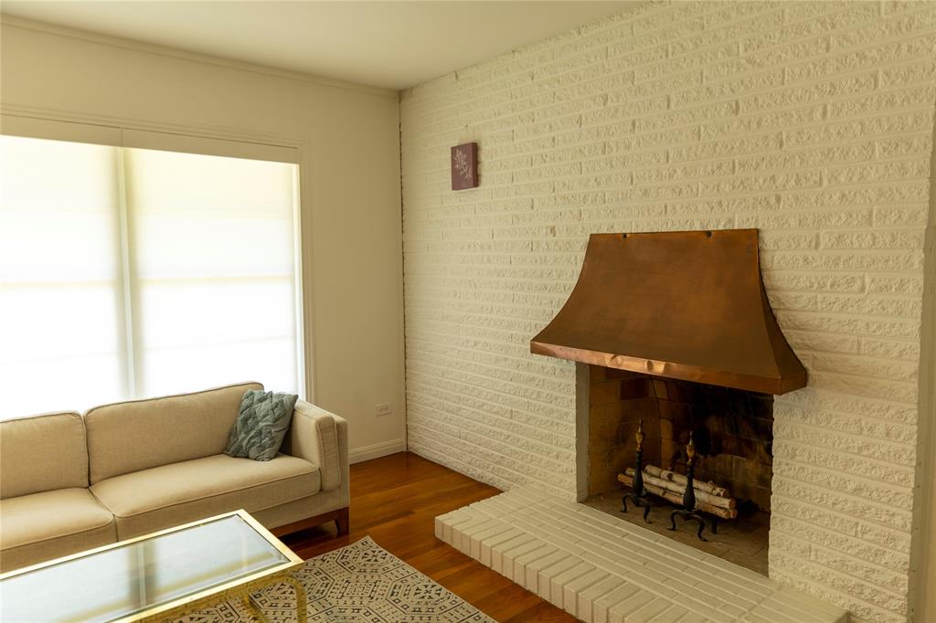 3228 Colcord Avenue Waco, TX 76707 - Photo 12 of 29 Living area featuring a painted brick fireplace with a copper hood and a brick hearth