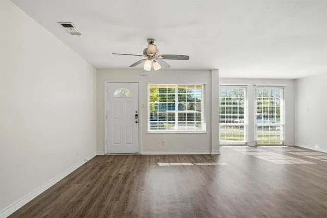 an empty room with wooden floor and windows