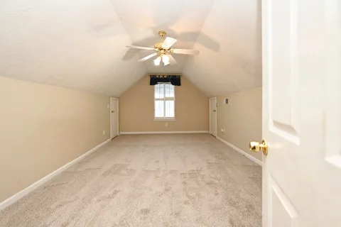 an empty room with a chandelier fan and windows