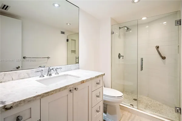 a bathroom with a granite countertop sink a toilet and shower