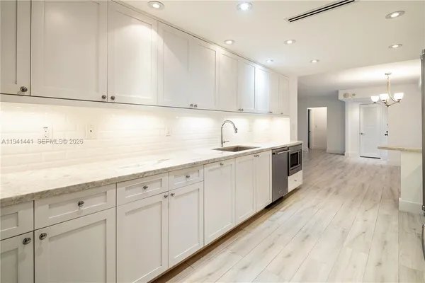 a kitchen with white cabinets appliances and sink