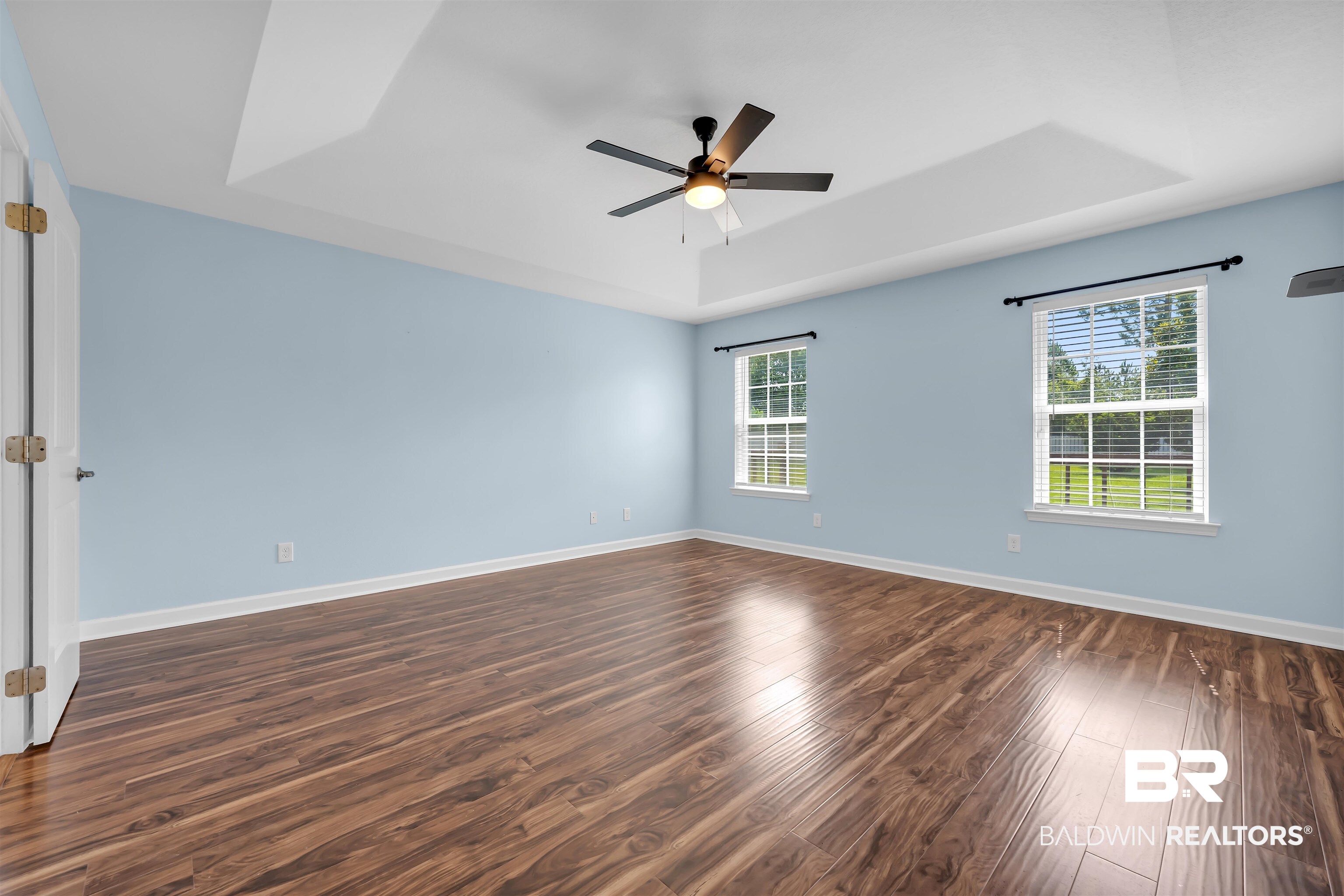 10147 Lyttleton Loop Lillian, AL 36549 - Photo 18 of 29 Spacious room featuring wood-finish flooring, a tray ceiling, two windows, and a ceiling fan