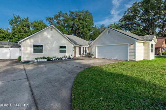 a view of a house with a yard and large tree