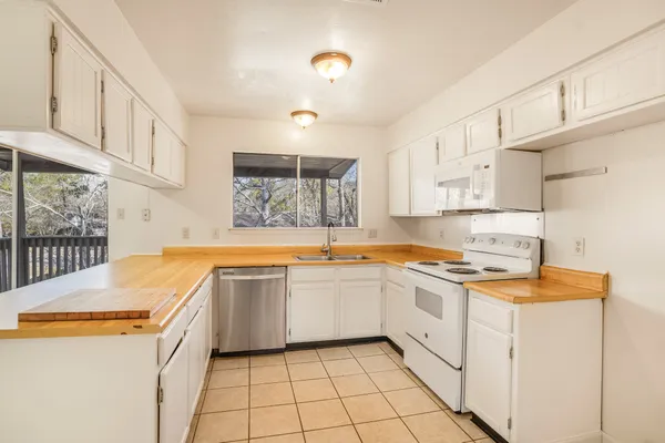 a kitchen with a sink a stove top oven and white cabinets