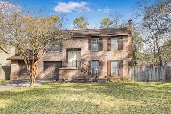 a front view of a house with a garden and tree