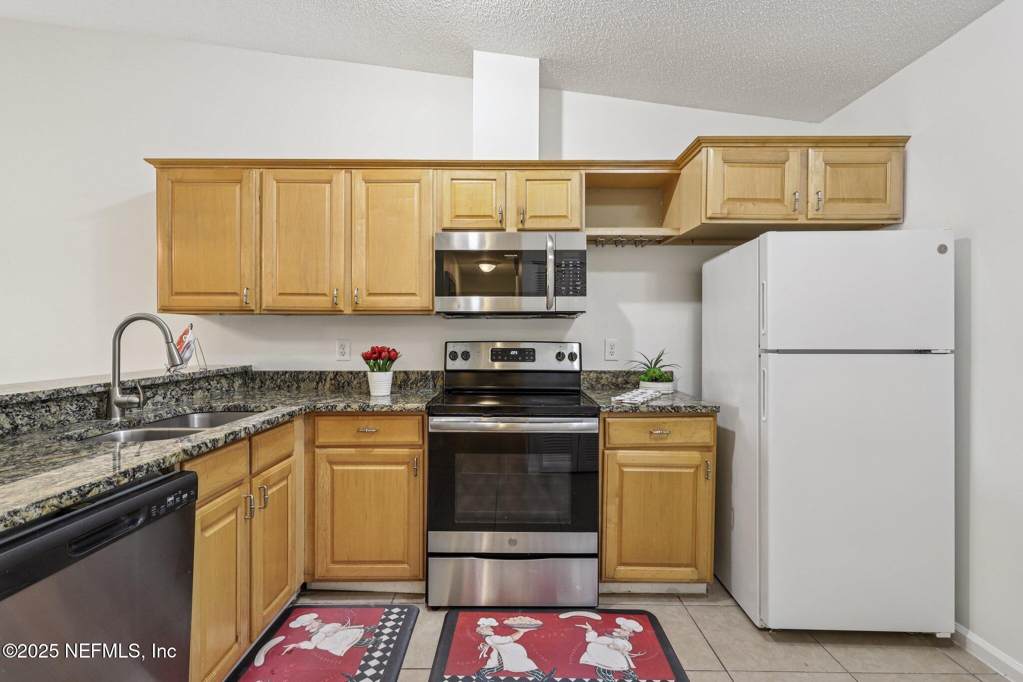 3801 Crown Point Road, Unit 2024 Jacksonville, FL 32257 - Photo 9 of 36 a kitchen with stainless steel appliances granite countertop a stove a sink and a refrigerator