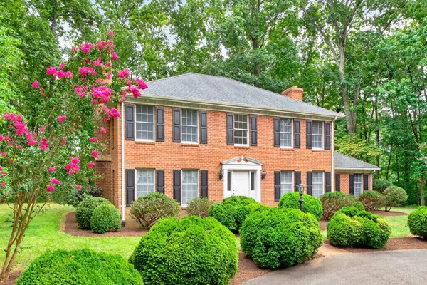 a front view of a house with a yard and fountain in front of house
