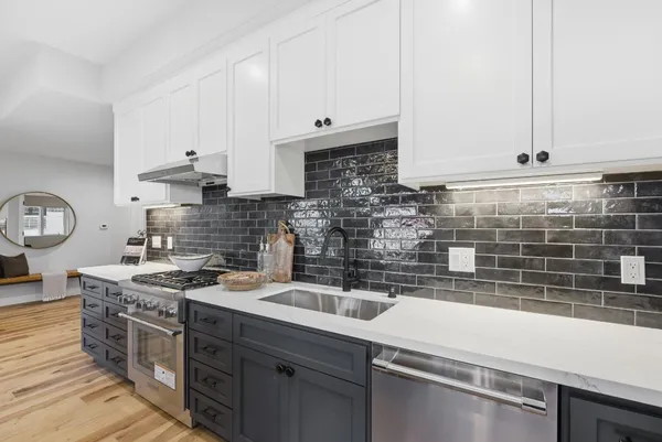 a kitchen with stainless steel appliances a sink a stove and white cabinets