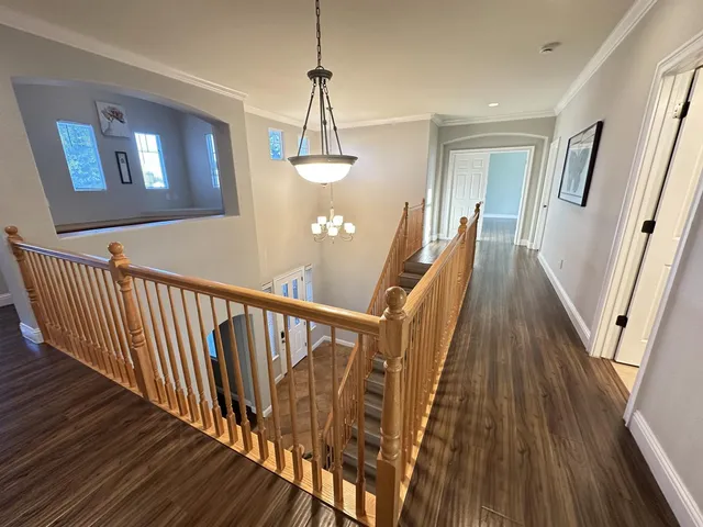 a view of a hallway with wooden floor and staircase