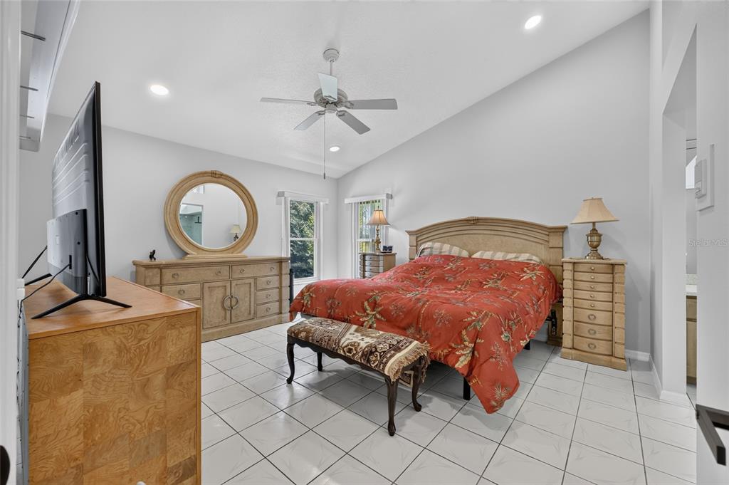 19025 Southwest 98th Loop Dunnellon, FL 34432 - Photo 28 of 80 a spacious bedroom with a bed a mirror and paintings on the wall