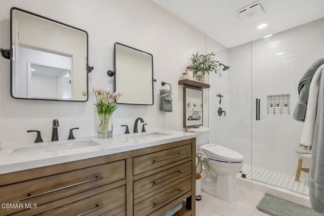 a bathroom with a toilet a sink a shower and a mirror