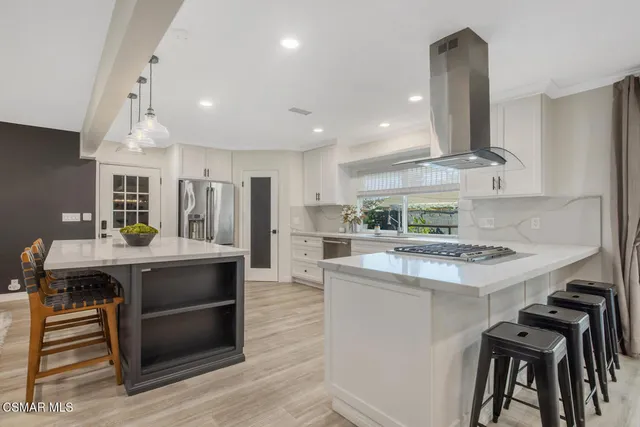 a kitchen with kitchen island a stove a sink a refrigerator and chairs
