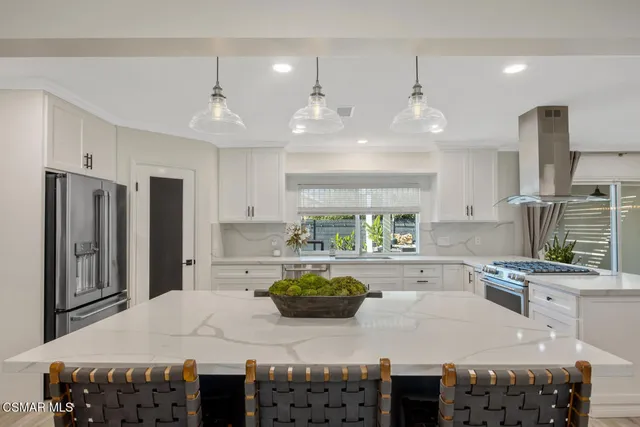 a kitchen with stainless steel appliances granite countertop a stove a refrigerator a sink dishwasher a dining table and chairs with wooden floor