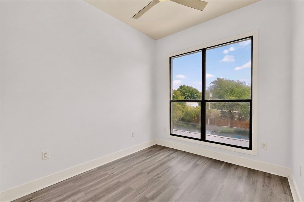 4414 Cedar Springs Road, Unit 318 Dallas, TX 75219 - Photo 29 of 40 Expansive window with black framing, wood-finish flooring, white walls, and a ceiling fan