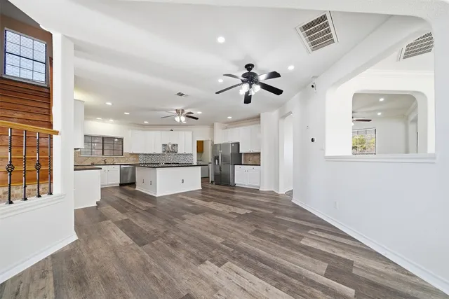 a large kitchen with kitchen island a stove a sink dishwasher and a refrigerator with wooden floor