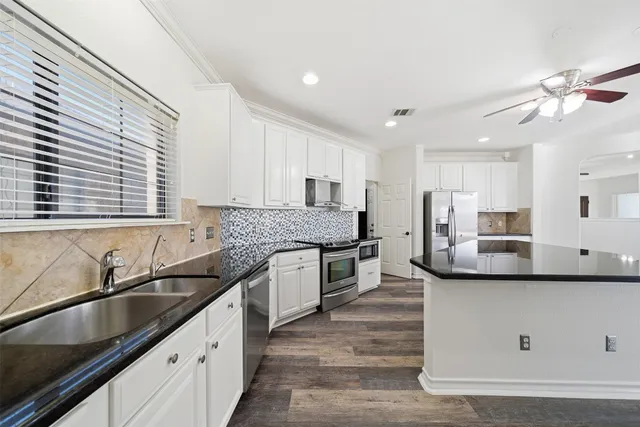 a kitchen with stainless steel appliances granite countertop a sink a stove and a refrigerator