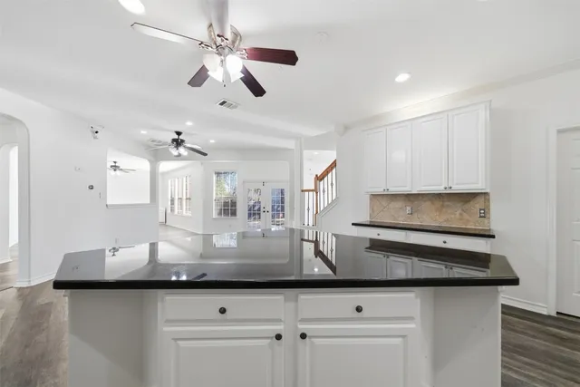 a kitchen with kitchen island granite countertop a sink cabinets and stainless steel appliances