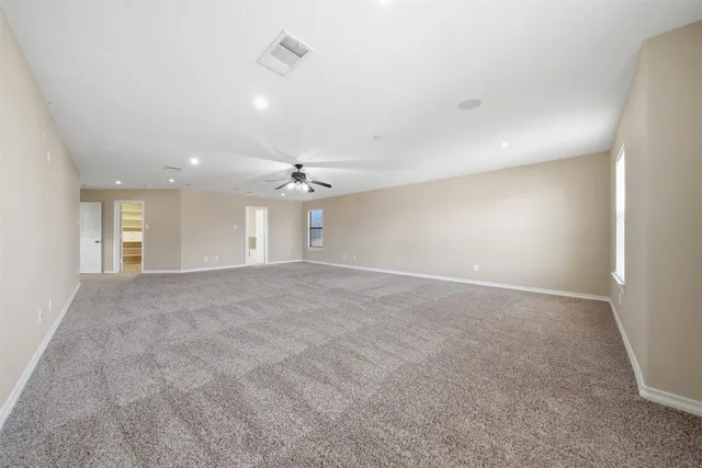 an empty room with windows and ceiling fan