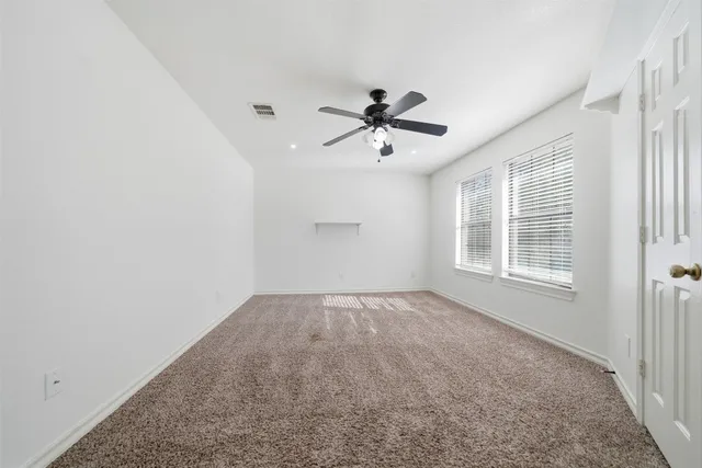 an empty room with wooden floor and ceiling fan