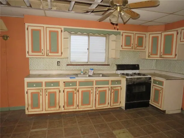 a white kitchen with stainless steel appliances a stove a sink and white cabinets