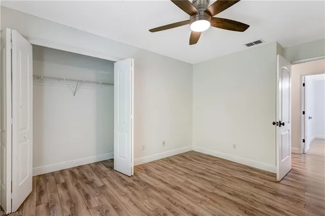 an empty room with wooden floor a ceiling fan and closet