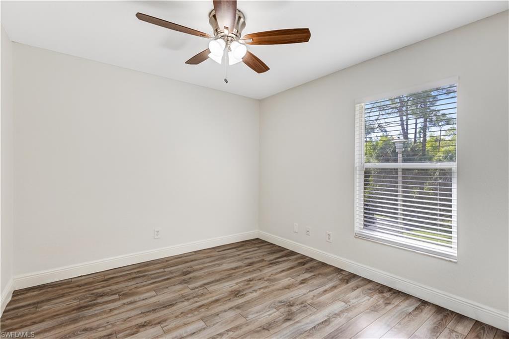 8285 Ibis Club Drive, Unit 807 Naples, FL 34104 - Photo 19 of 42 an empty room with wooden floor chandelier fan and windows