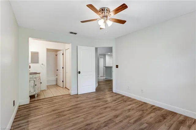 an empty room with wooden floor and a ceiling fan