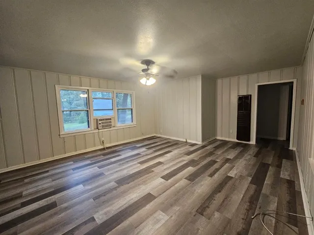 a view of an empty room with window and wooden floor