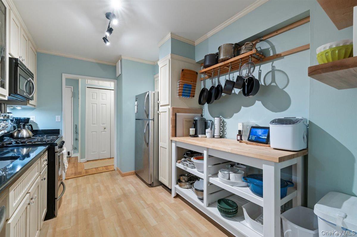 700 Shore Road, Unit 7Y Long Beach, NY 11561 - Photo 12 of 31 Kitchen featuring appliances with stainless steel finishes, track lighting, ornamental molding, light wood-style flooring, and open shelves