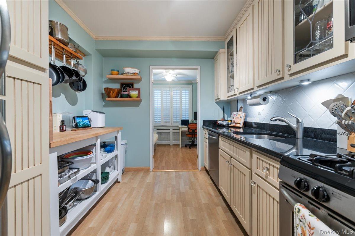 700 Shore Road, Unit 7Y Long Beach, NY 11561 - Photo 15 of 31 Kitchen featuring cream cabinetry, a desk, light wood-type flooring, dark stone counters, and glass insert cabinets